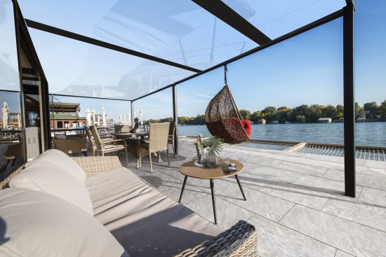 Sofa and hammock chair on terrace next to river Ambientebild Concreto Massivverbundplatte Farbvariante Granito Gris